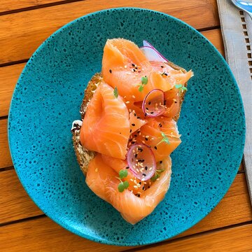 Gourmet Smoked Salmon Toast with Radish, Sesame Seeds and Microgreens on Turquoise Plate