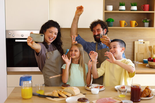 Happy family celebrating together around the kitchen table during breakfast