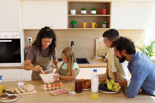 Family preparing homemade breakfast together in a bright modern kitchen