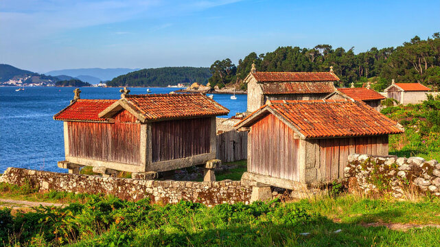 Traditional stone granaries near the ocean in a sunny coastal landscape