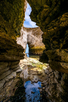 View from inside a dramatic sea cave at Flamborough Head on the Yorkshire coast of England. Eroded chalk cliffs, rock pools and a natural opening towards the North Sea.