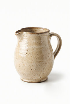 Ceramic pitcher with a rustic finish on a white background