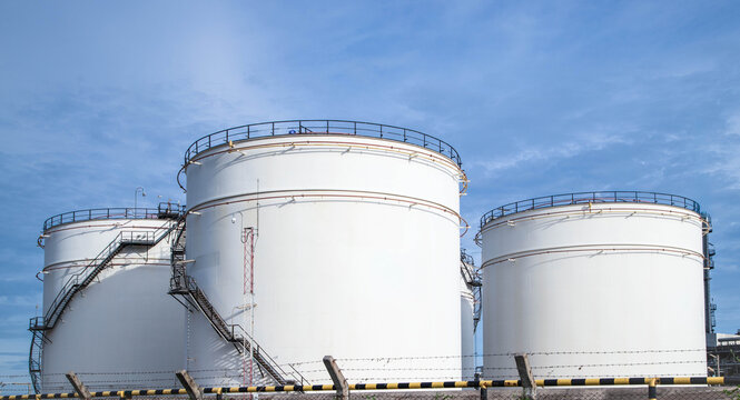Crude Oil Industry, White Storage Fuel Gas Container Tanks in Petroleum Refinery Industrial Factory area against Blue Sky Background