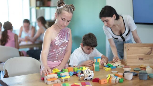 In childrens leisure club, preteens play at table, they stack pyramids, solve puzzles, construct, play with wooden cubes. Summer vacation activity, vacation leisure