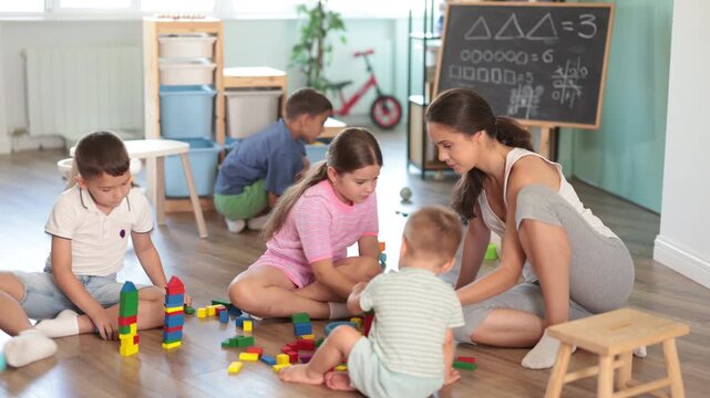 Friendly diverse kids having fun with educational games in cozy kindergarten classroom