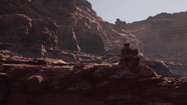 The sun is shining on tall cliffs and rock formations in a desert area. Shadows are cast across the rugged terrain. The scene shows the natural beauty of the landscape.