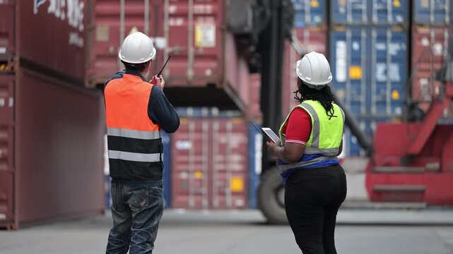 Logistics workers review operational data while inspecting shipping containers at a cargo yard. Concept of supply chain, freight transport, warehouse operations, teamwork, and logistics management.