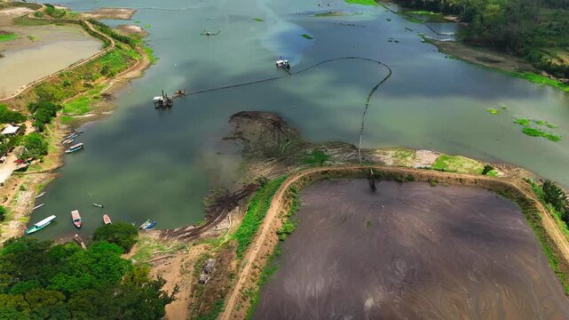 Aerial view of specialized suction dredges and floating platforms extracting sediment and debris from the Sengguruh reservoir bed in Malang, East Java, Indonesia.