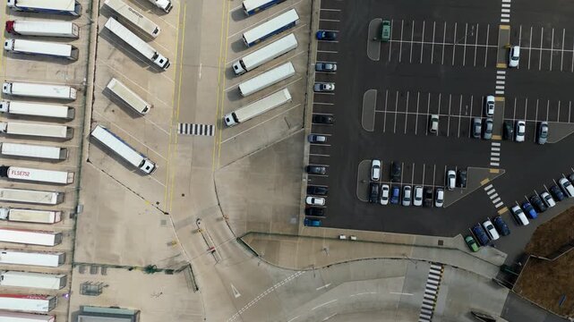 Aerial view of a parking lot featuring numerous semi trucks and parked cars arranged in rows on a paved surface in Luton, England, United Kingdom.