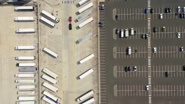 Aerial view of a parking lot filled with semi trucks and cars parked in orderly rows on asphalt in Luton, England, United Kingdom.