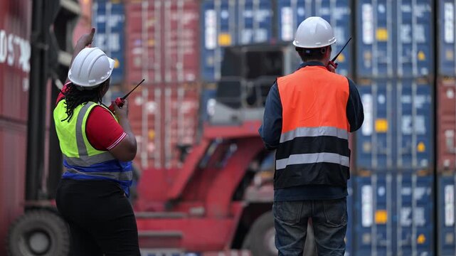 Logistics workers review operational data while inspecting shipping containers at a cargo yard. Concept of supply chain, freight transport, warehouse operations, teamwork, and logistics management.