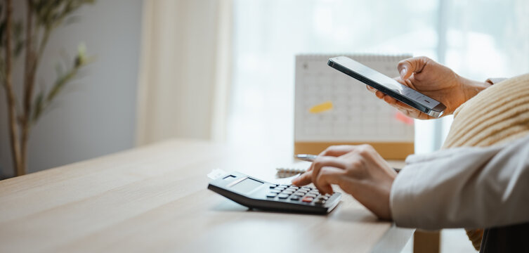 A person uses a smartphone and calculator for finance planning as digital payment connects banking with transaction and app tools, helping manage card, bank funds and shopping within mobile finance.