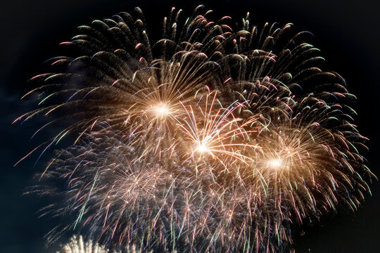 Brilliant golden sparks explode across the dark night sky creating beautiful patterns of light during a lively celebration for Independence Day in America