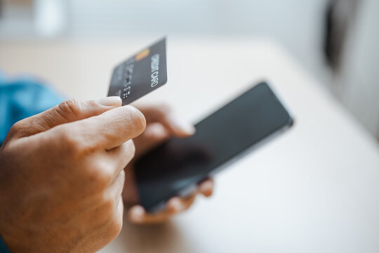 A person holds a card beside a smartphone wallet, using credit for digital payment and banking transaction needs while managing money, finance, balance and funds for shopping and credit use.