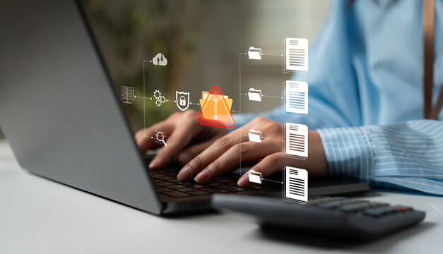 Business professional using a laptop with cybersecurity warning and digital file icons, representing data protection, security threats, privacy risk, network defense and information security.