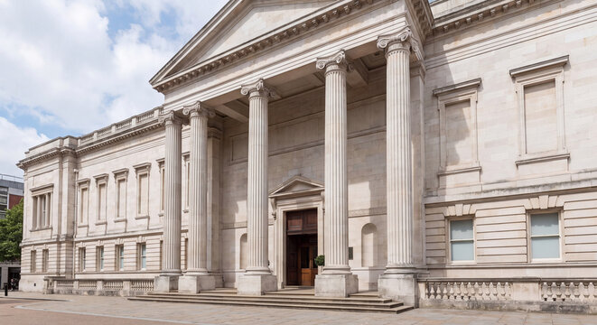 Low angle exterior view of a monumental neoclassical museum building featuring grand stone columns decorative pediment and architectural stone carvings