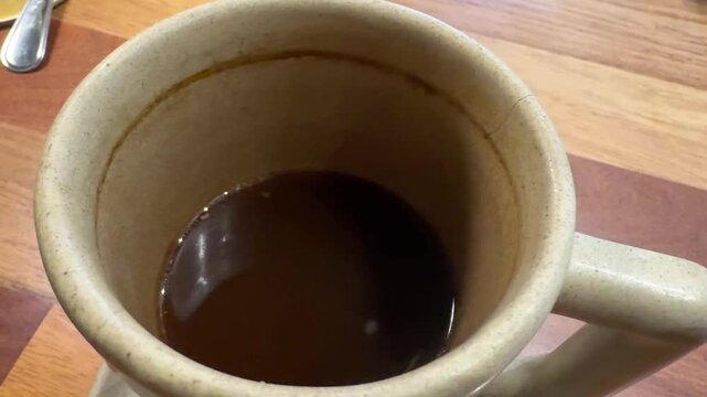 Freshly Brewed Coffee Half Empty or Half Full  in Ceramic Cup on Table in a Coffee Shop