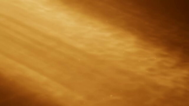 Golden orange abstract texture with soft swirling patterns shifting through warm cloudy light