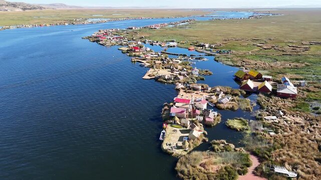 Cinematic aerial view over the unique Uros floating reed islands on the deep blue waters of Lake Titicaca, Peru.