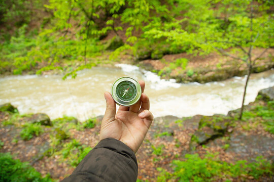 Male hand showing compass in the forest.