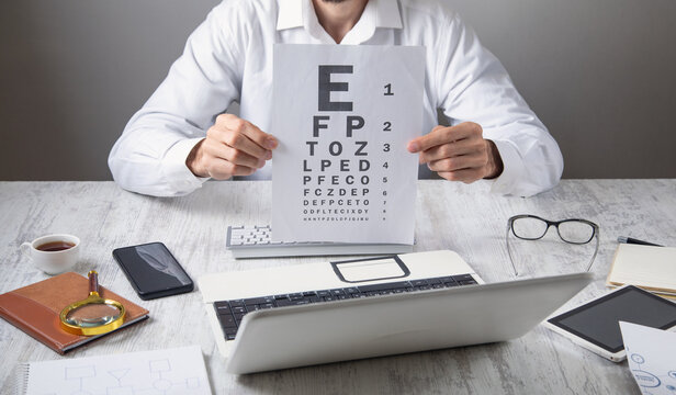 Caucasian doctor showing eye examination test in the workplace.