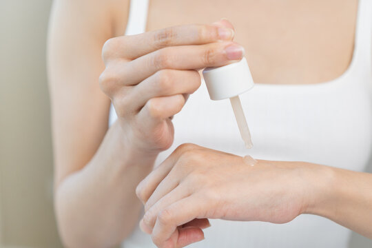 Happy beauty routine, asian young woman, girl dropping collagen moisturizer on her hand from pipette, applying vitamin using oil serum on face moisturizing for hydrating skin, isolated on background.