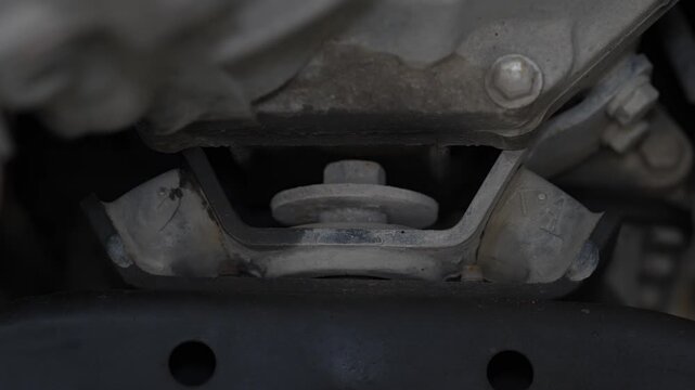 A rubber engine or transmission mount with a large central retaining bolt connecting the gearbox to the car subframe.