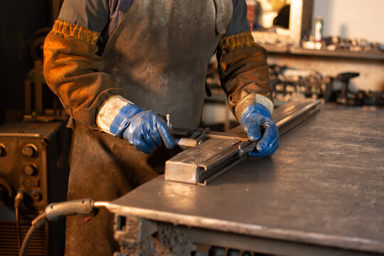 Close up of gloved hands securing metal pieces with clamp