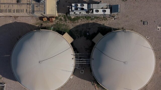 Aerial view of large circular biogas digester tanks and industrial infrastructure at a farm in Milan, Lombardy, Italy.