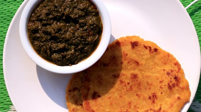 Homemade fresh corn flour chapati or paratha and sarso ka saag with butter table top spin.