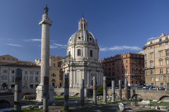 View of Trajan's Column and the church of Santa Maria di Loreto standing amidst historic buildings under a clear blue sky in Rome, Lazio, Italy.