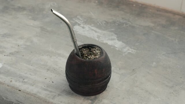 Male hand reaching for and taking a traditional calabash gourd with bombilla for drinking mate