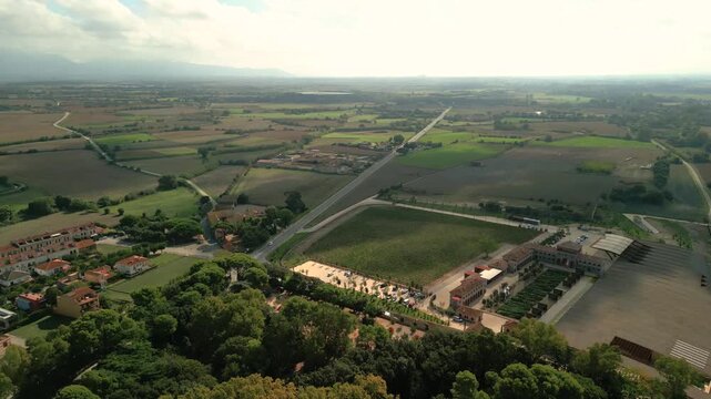 Aerial view of the historic Peralada Castle grounds surrounded by lush trees, vineyards, and agricultural fields in Peralada, Catalonia, Spain.