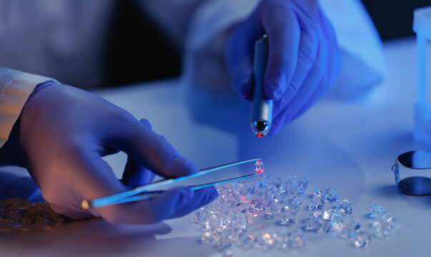 Gemologist laboratory detailed closeup inspecting loose diamonds with handheld laser for clarity and cut analysis using microscope for jewelry quality control poster