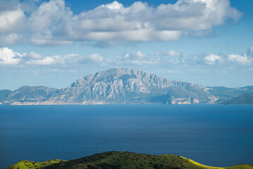 View across the Strait of Gibraltar from Mirador del Estrecho, Spain, towards the mountains of Morocco. Rolling green hills, deep blue sea and scattered clouds under clear daylight © ihervas