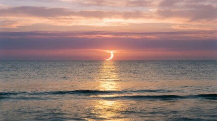 Fototapeta premium Crescent sun setting over calm ocean with golden reflection and soft waves