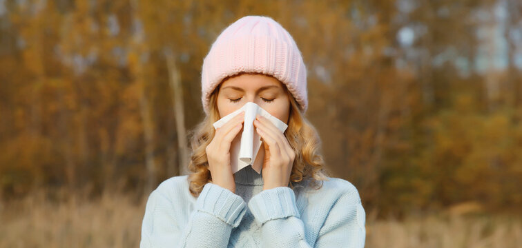 Sick woman sneezing blow nose using tissue, unhealthy suffering girl feels unwell outdoors