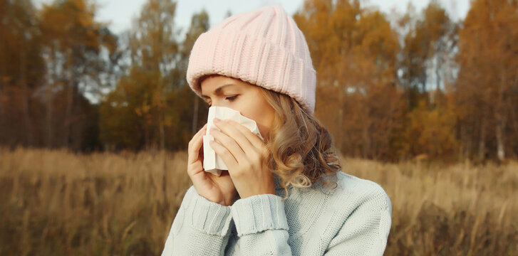 Sick woman sneezing blow nose using tissue, unhealthy suffering girl feels unwell outdoors