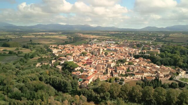 Aerial view of the historic town of Peralada featuring stone buildings, narrow streets, and surrounding lush green landscape in Peralada, Catalonia, Spain.