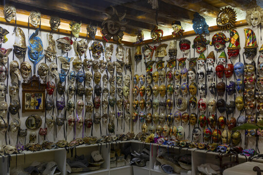 View of a wide collection of traditional Venetian masks displayed on a wall in a shop in Venice, Veneto, Italy.