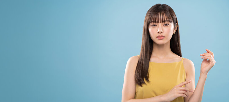 黄色のトップスを着て腕に手を添える落ち着いた表情の女性
