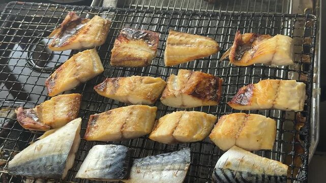 Japanese chef grilling salted mackerel saba fillets on a wire mesh for bento side dish, izakaya kitchen, Japan