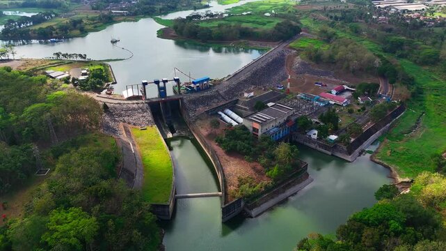 Aerial view of PLTA Sengguruh hydroelectric power plant situated on the river with surrounding lush vegetation and infrastructure in Malang, East Java, Indonesia.