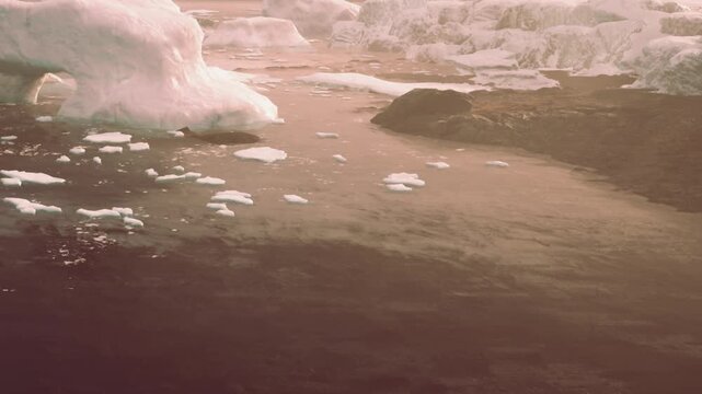 Icebergs float in a river at sunset. The water reflects soft colors from the sky. The landscape shows a mix of ice and land with a distant horizon.