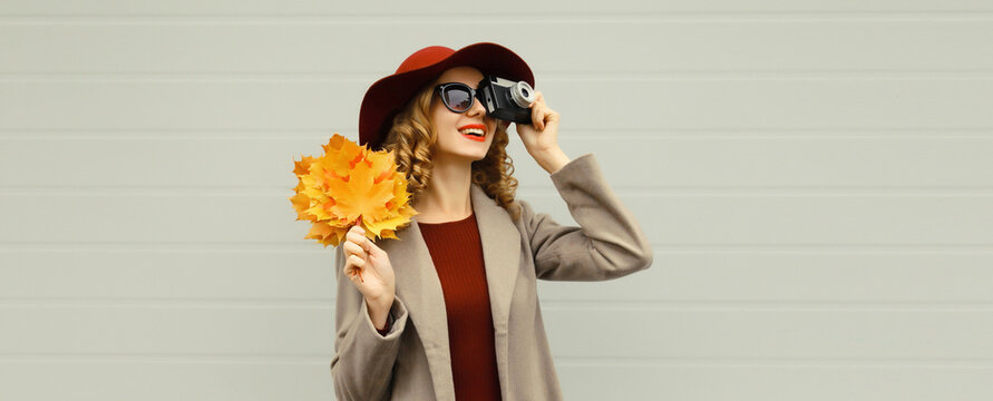 Beautiful happy woman photographer taking picture with camera, stylish girl, autumn yellow leaves