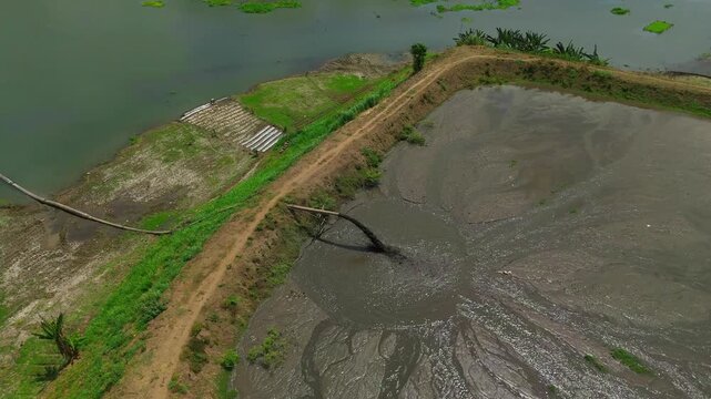 Aerial view of a pipeline discharging dredged sediment into a reservoir basin to maintain water capacity in Malang, East Java, Indonesia.