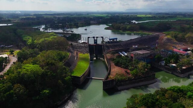 Aerial view of PLTA Sengguruh hydroelectric power plant with dam structure and reservoir surrounded by lush greenery in Malang, East Java, Indonesia.