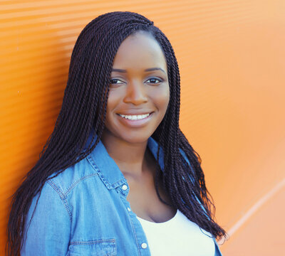 Portrait of happy stylish young African woman, black girl smiling posing in the city