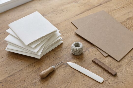 Hand bookbinding tools with folded paper on rustic wood