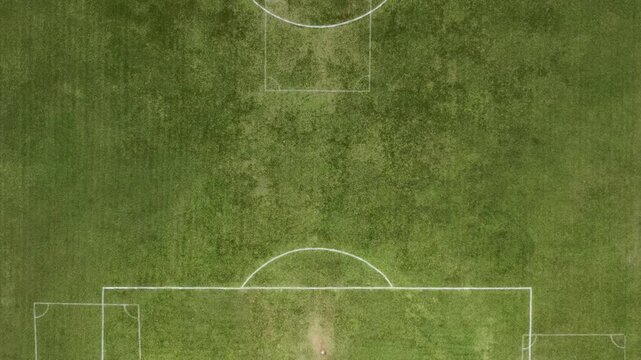 Aerial view of a green soccer field with white boundary lines and a center circle on the grass in Brazil.